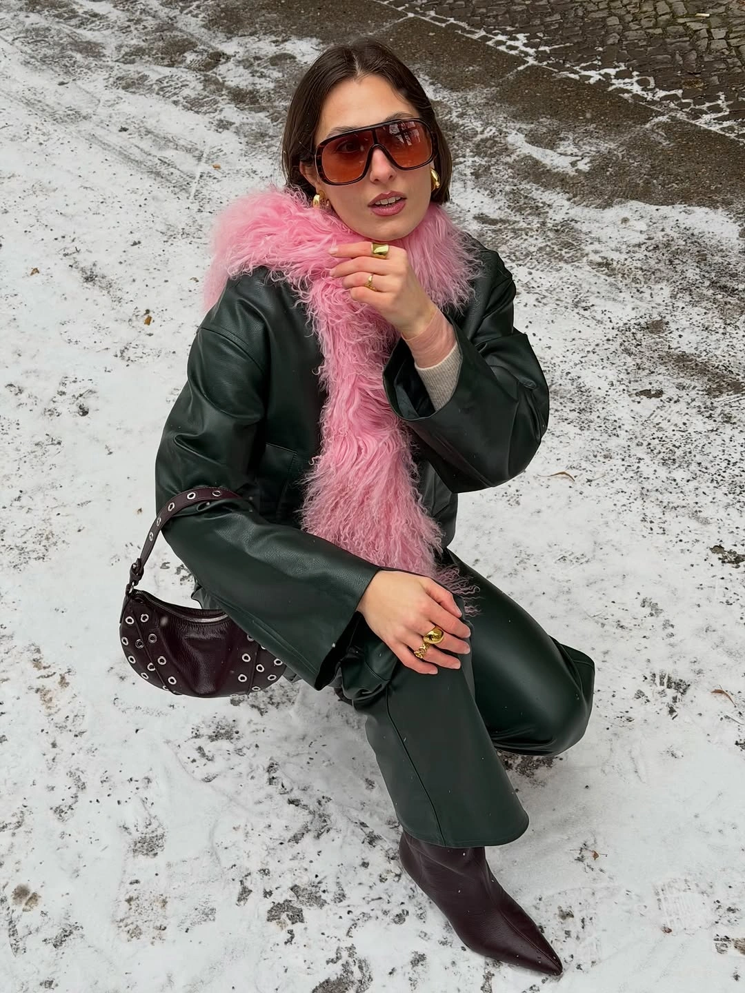 Dark green jacket and trousers with pale pink scarf, brown boots, and studded bag