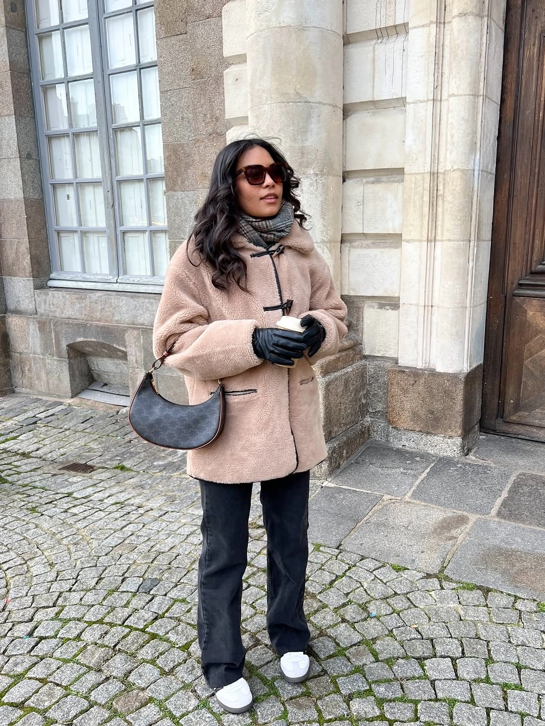 Taupe textured jacket with dark trousers, gray scarf, white sneakers, and shoulder bag
