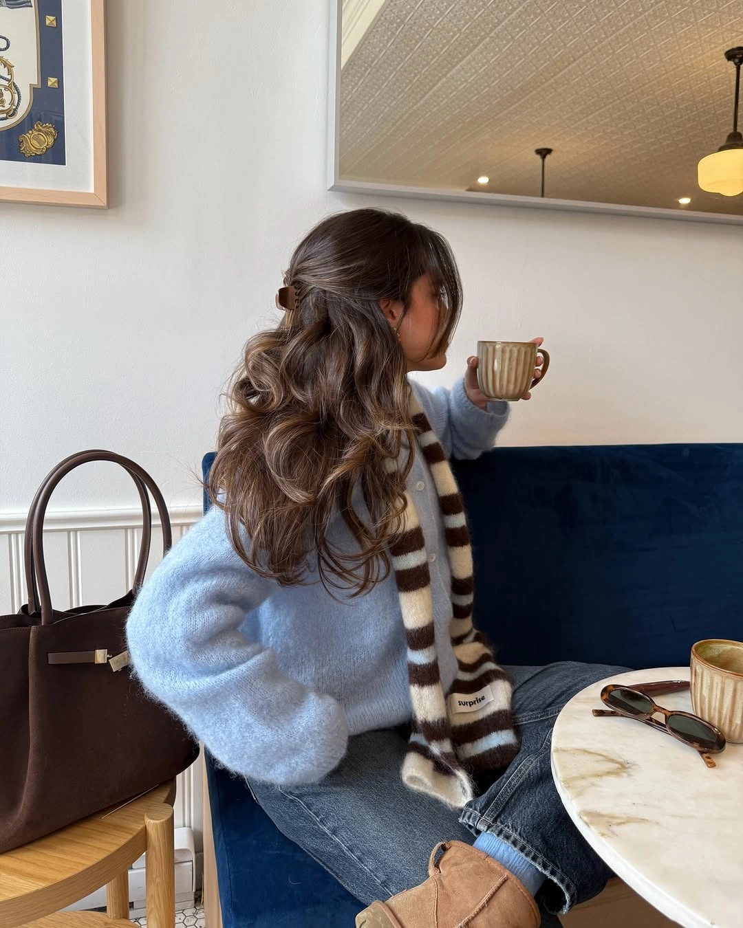 Powder blue fuzzy sweater with striped scarf, blue jeans, and tan boots