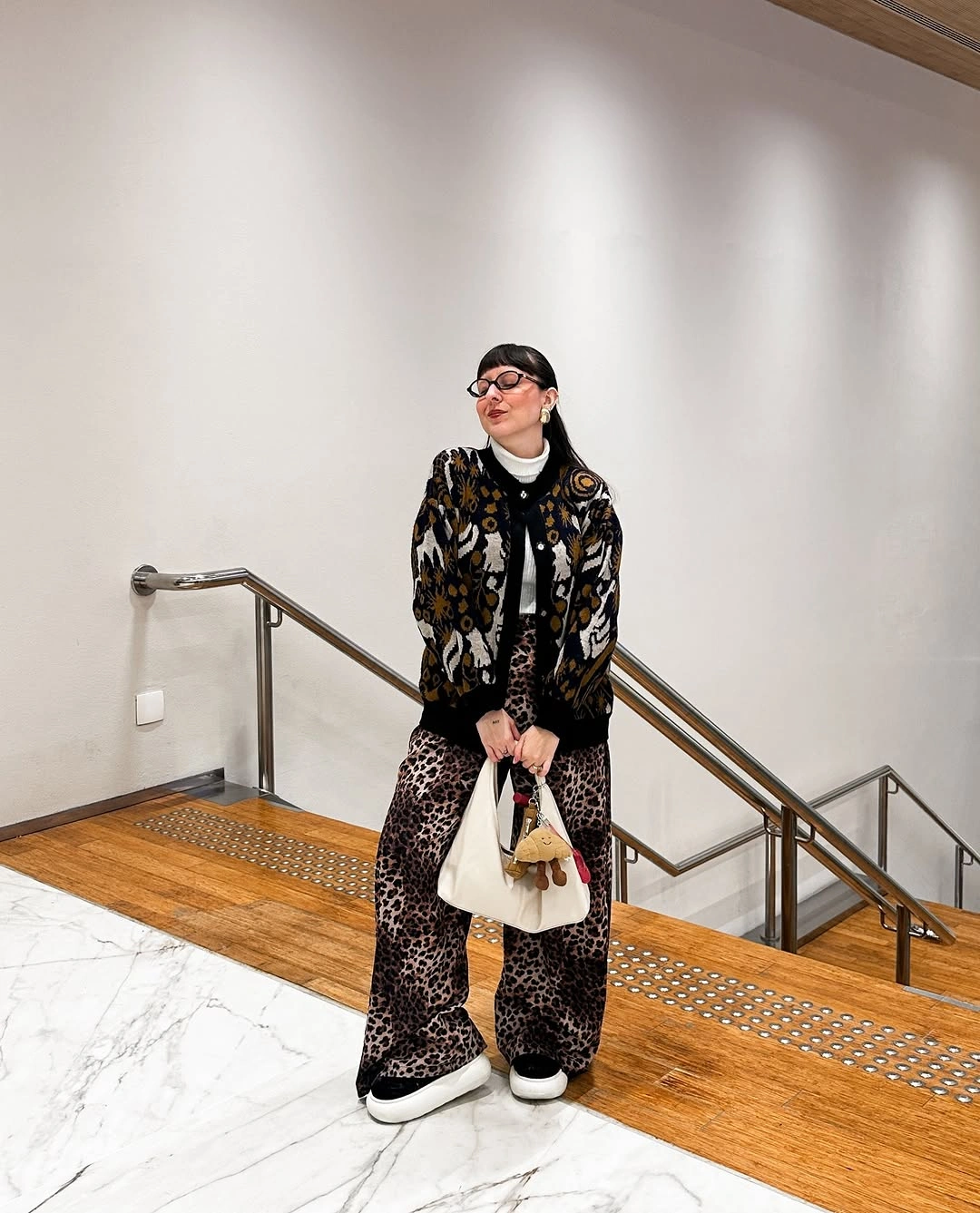 Leopard print jacket and trousers with black turtleneck, dark shoes, and small white bag
