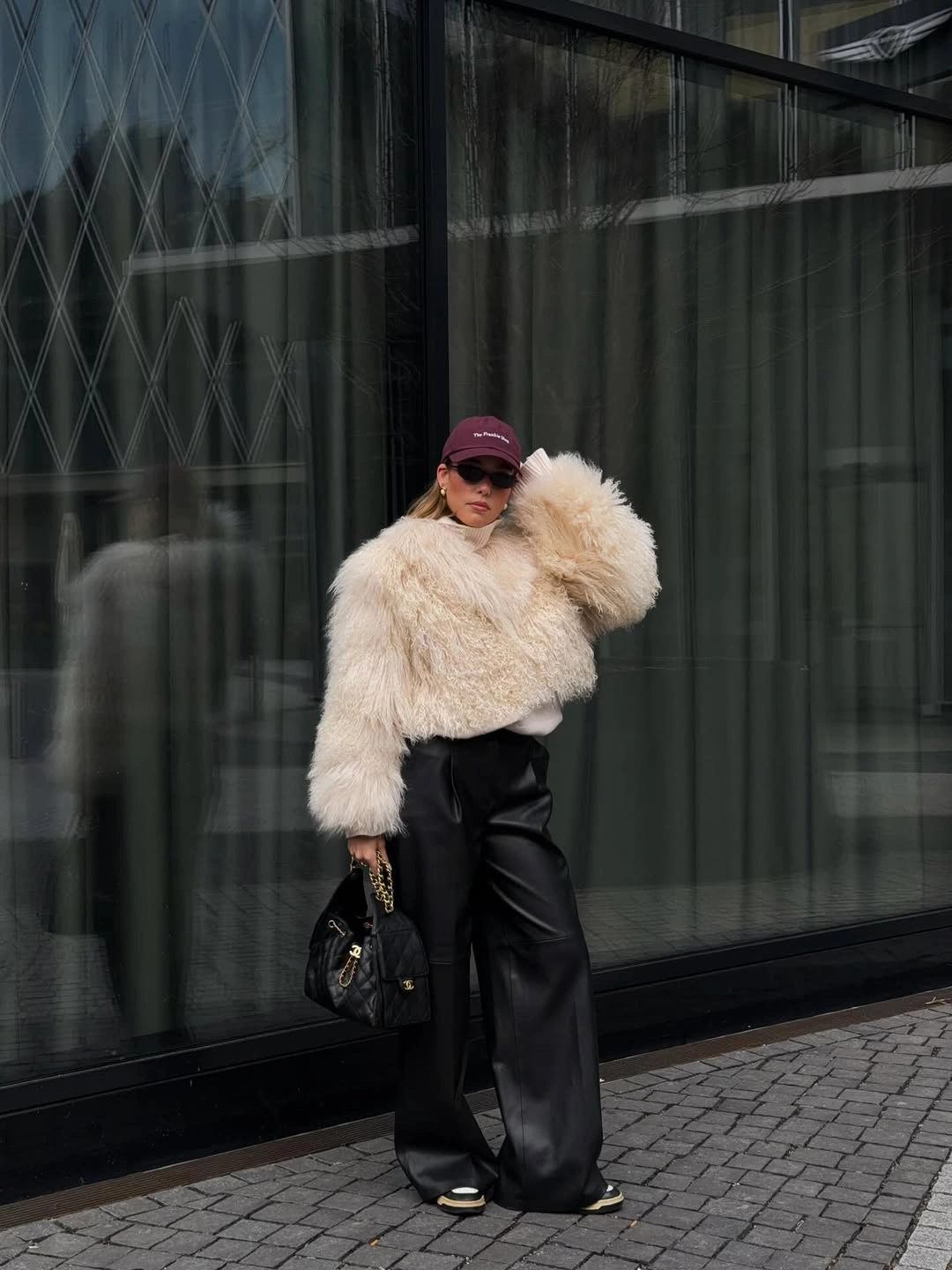 Cream shaggy jacket with black wide-leg trousers and burgundy cap