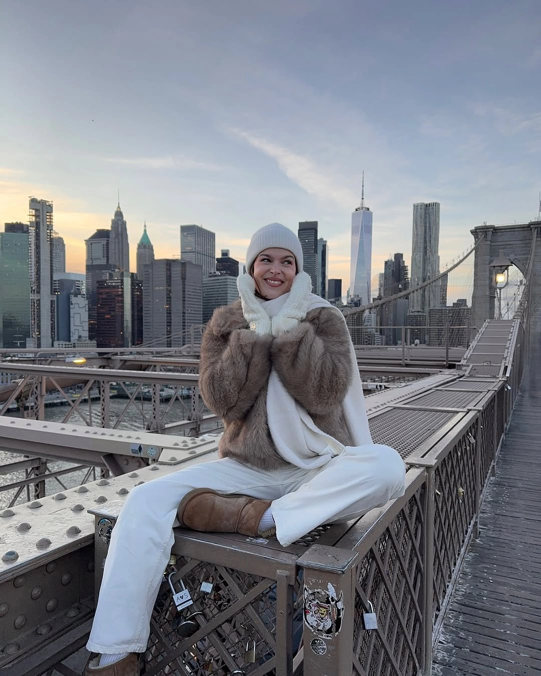 Taupe textured jacket with cream scarf, white trousers, beanie, and tan boots