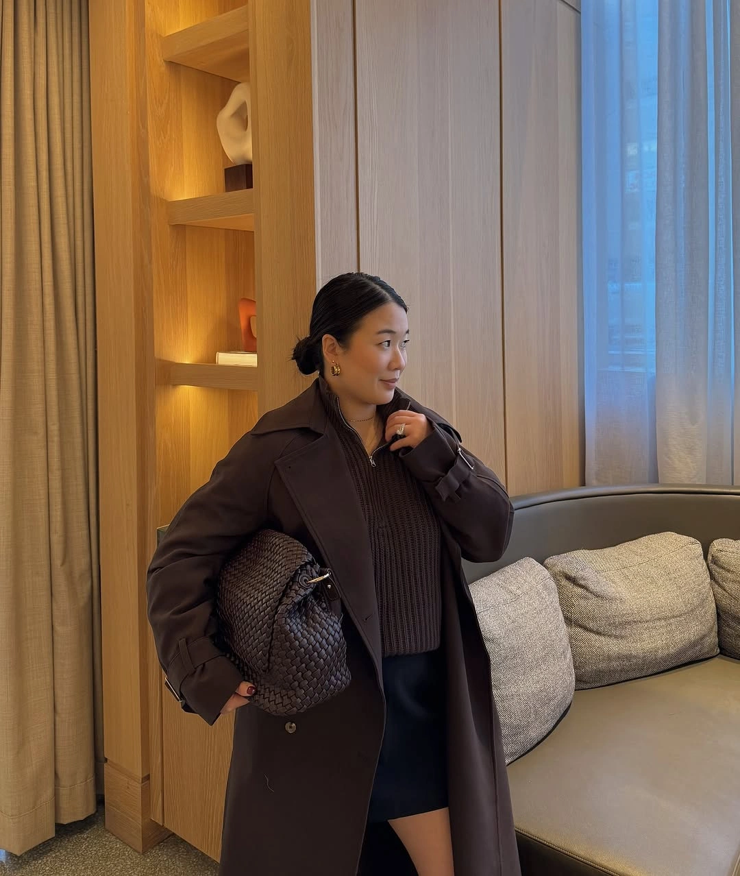 Dark-brown coat with ribbed zip knit, woven bag, and short dark garment