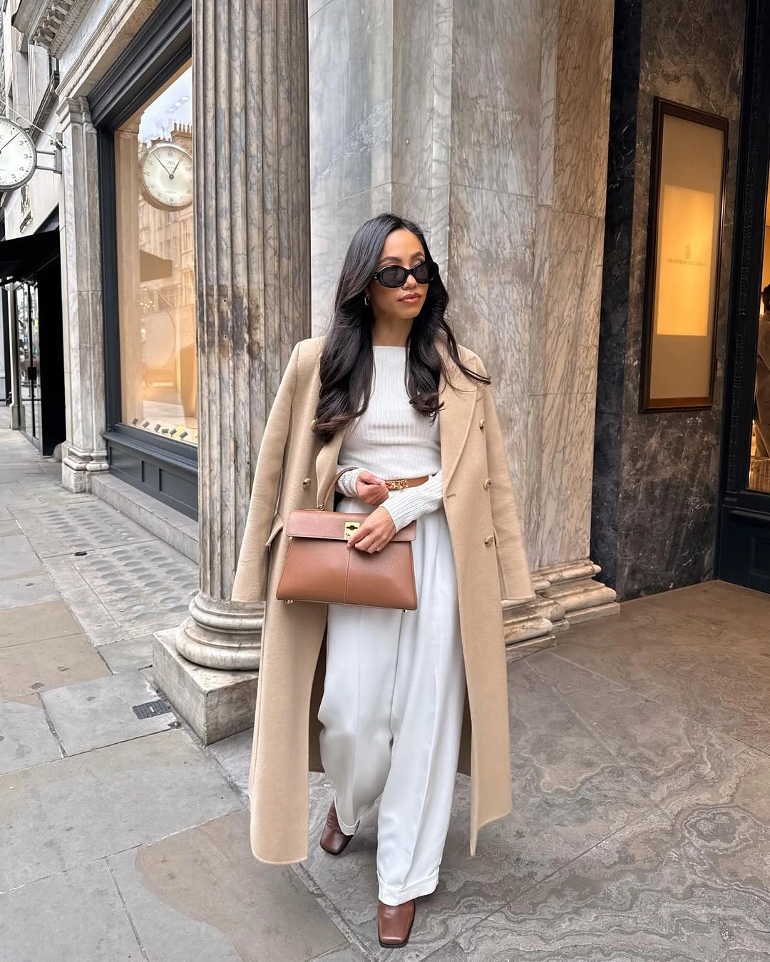 Camel coat over white separates with a brown belt and structured handbag