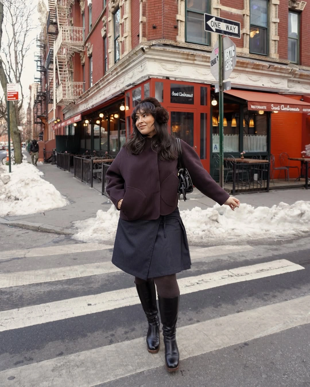 Plum jacket with striped skirt, dark tights, knee-high boots, and earmuffs