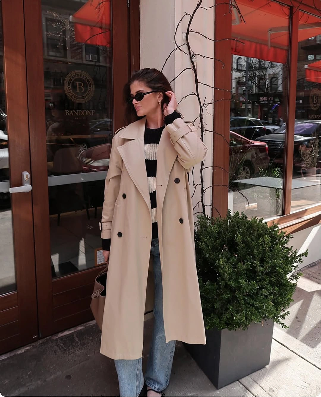 Beige double-breasted coat over a striped knit and blue jeans