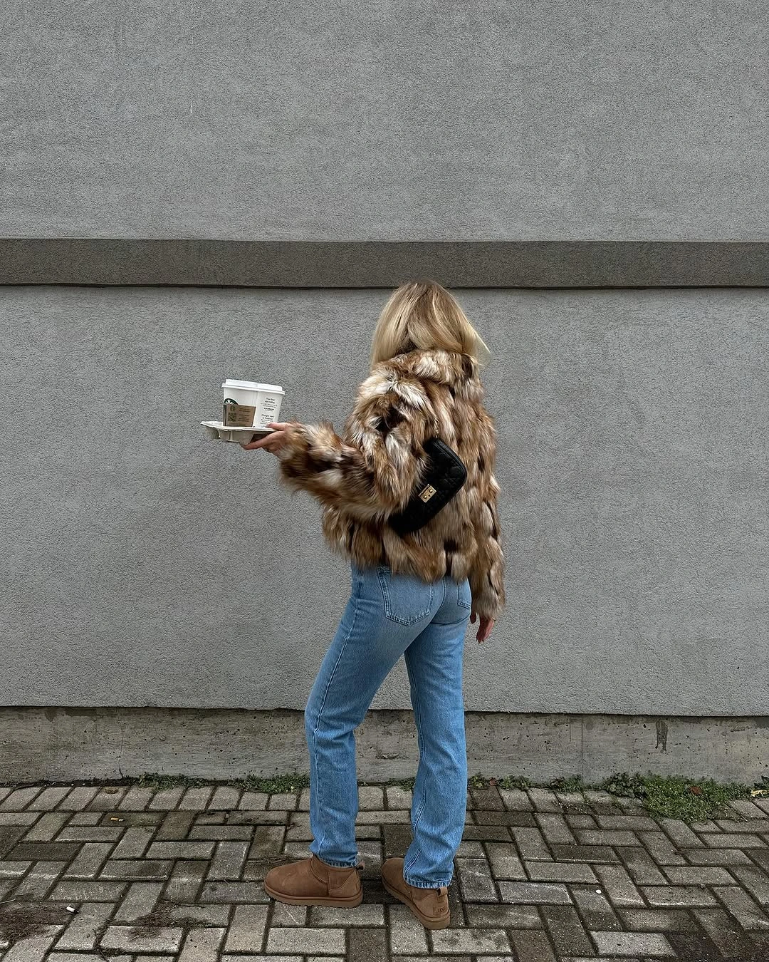Mottled brown jacket with straight blue jeans, black bag, and tan boots