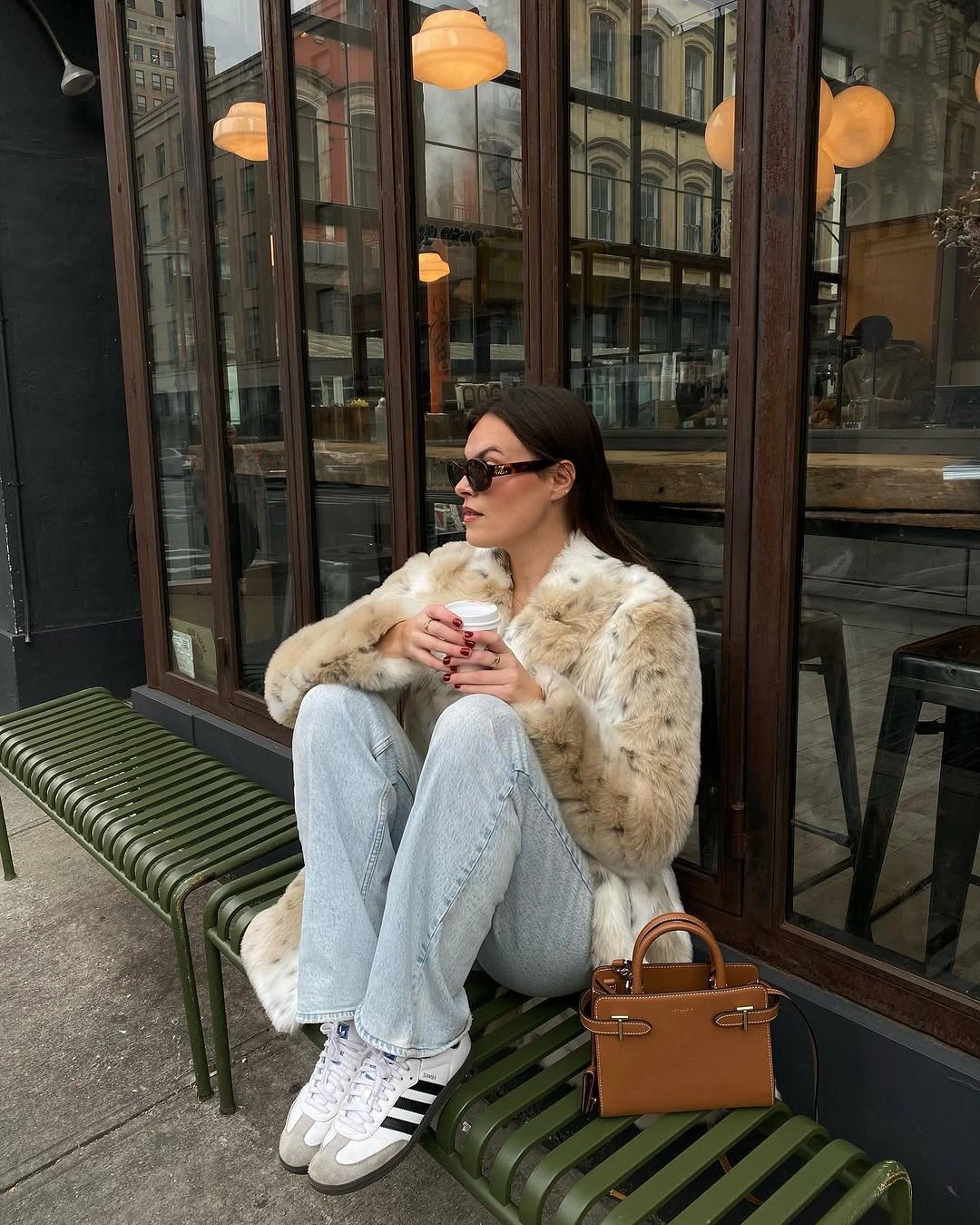 Pale textured outerwear with light jeans, striped sneakers, and caramel handbag