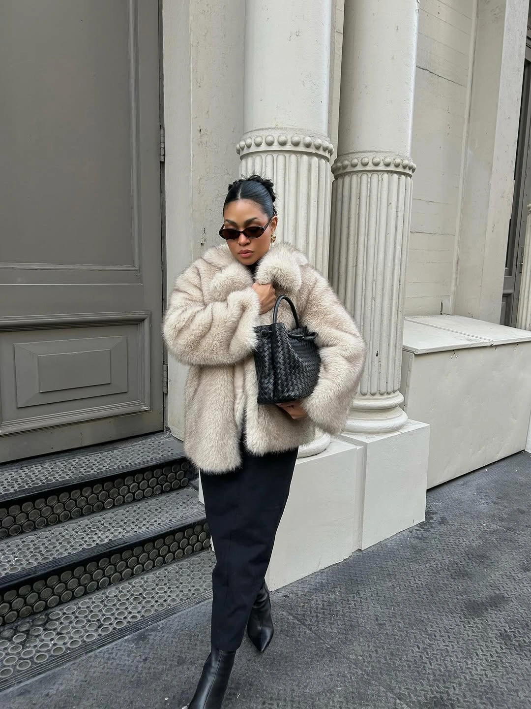 Pale textured jacket with black midi skirt, pointed boots, and woven bag