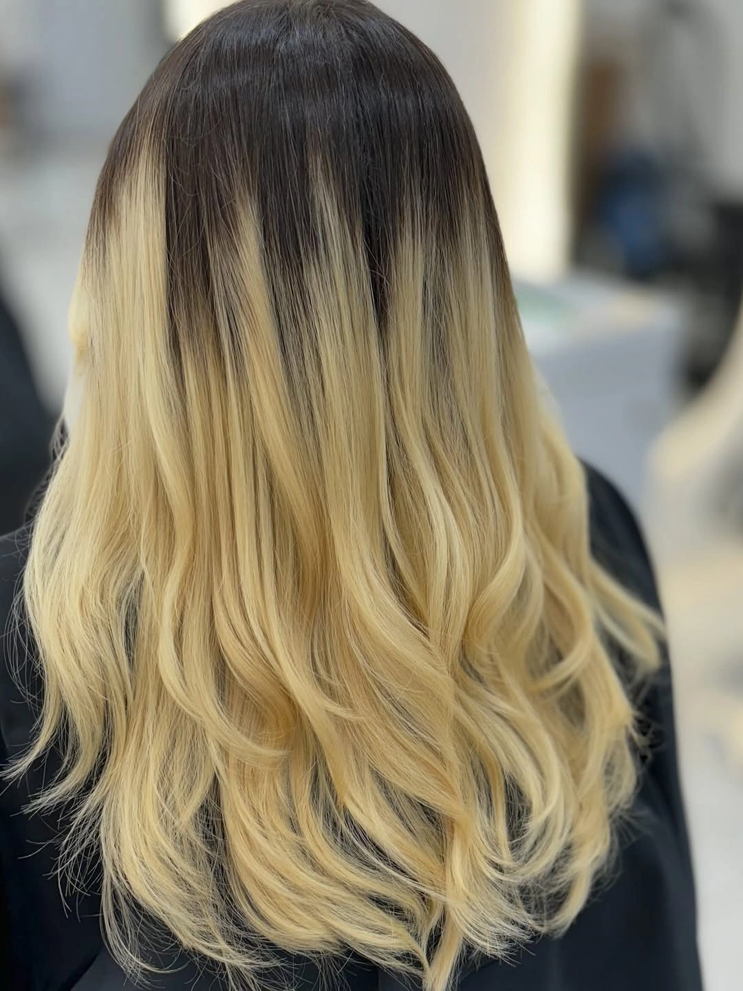 Long blonde wavy hair with dark root contrast