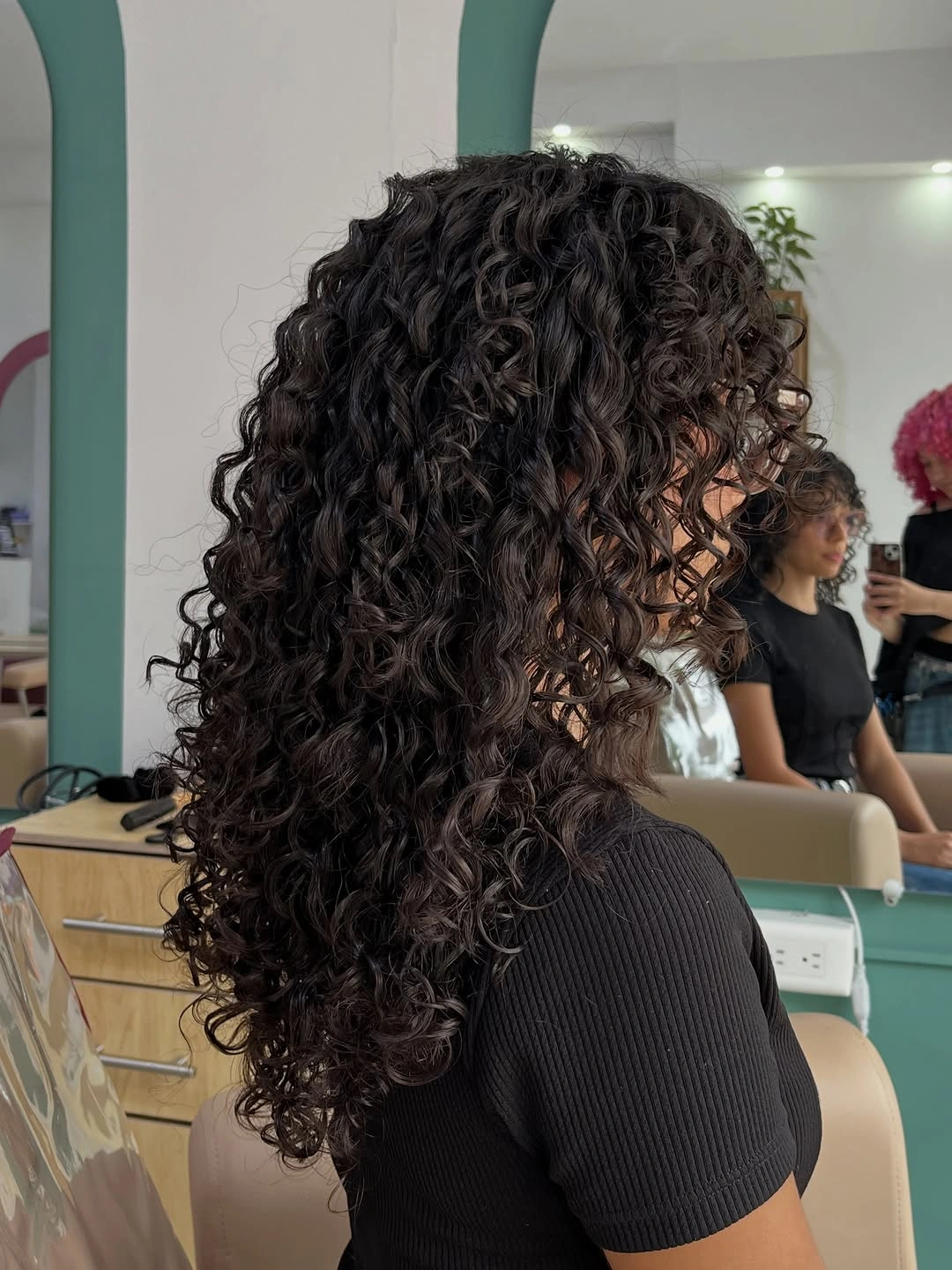 Dark curly medium long haircut shown from side
