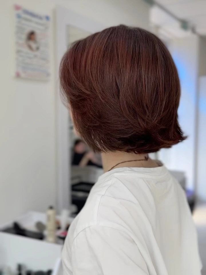 Short auburn rounded bob with flipped lower edge