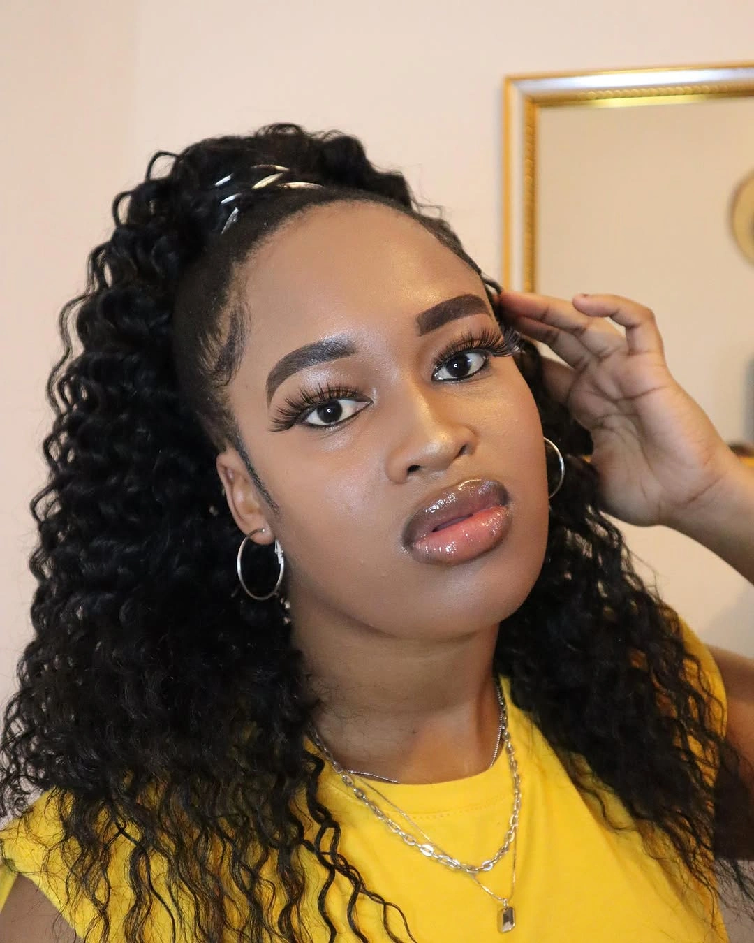 Black curly lifted hairstyle with gold toned accents