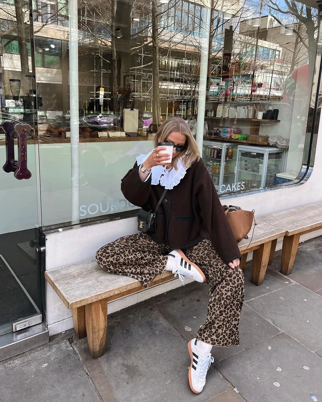 Brown jacket, ruffled white blouse, leopard-print trousers, and white sneakers