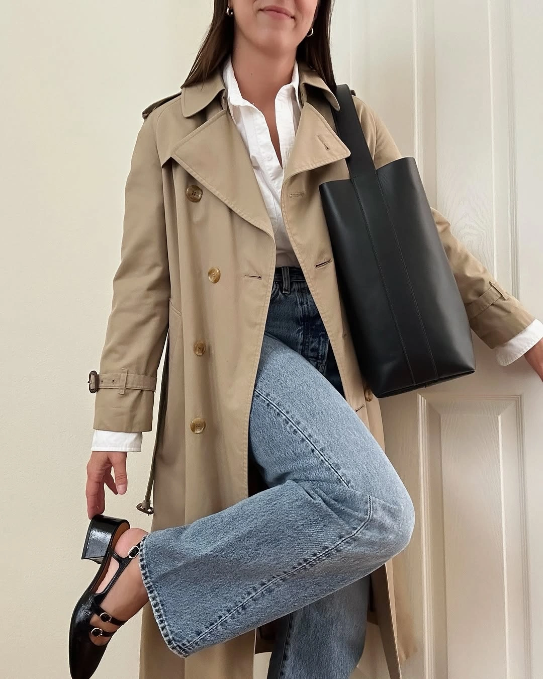 Beige trench-style coat, white shirt, blue jeans, black flats, tote