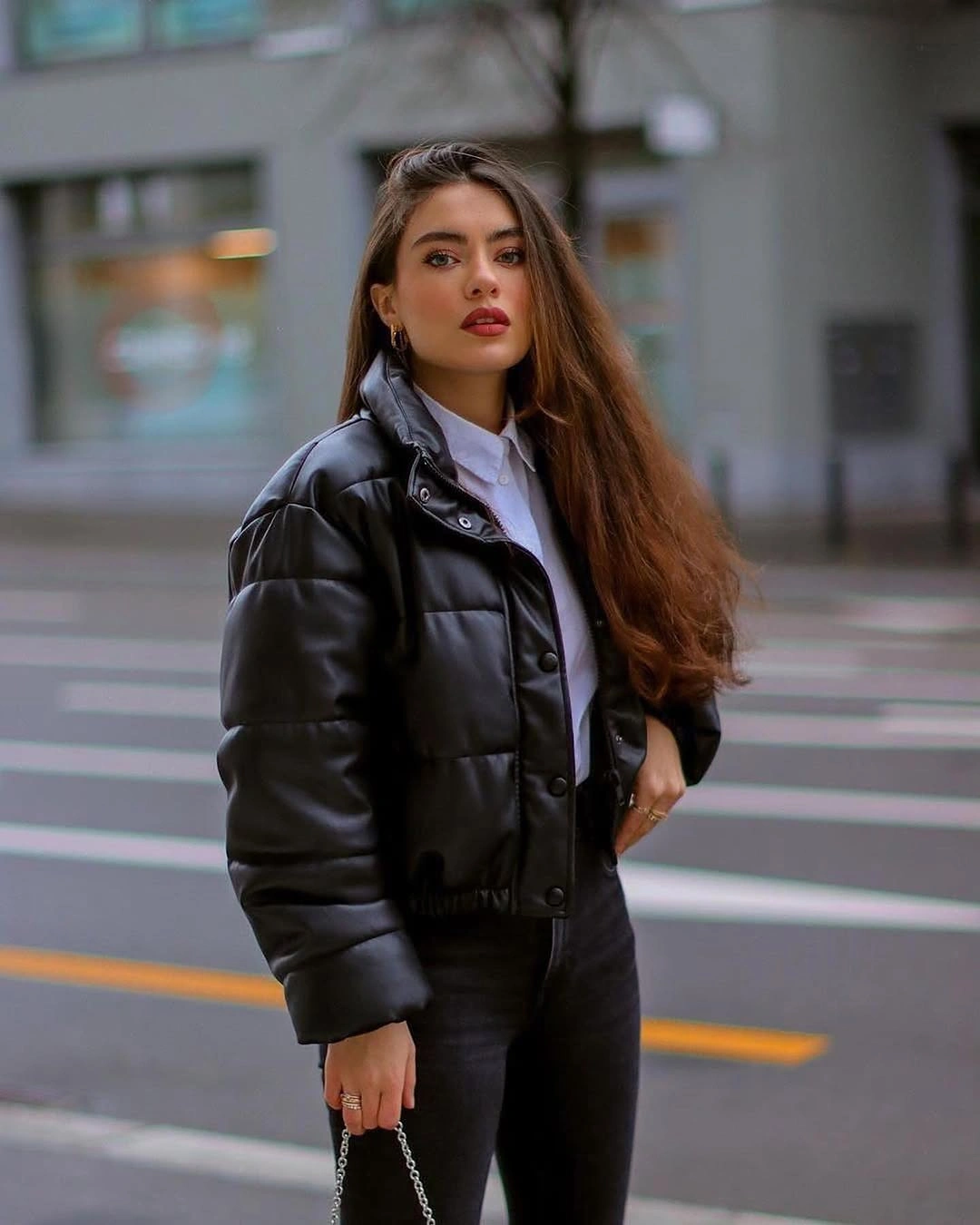 Glossy-looking black padded jacket over white shirt and dark trousers
