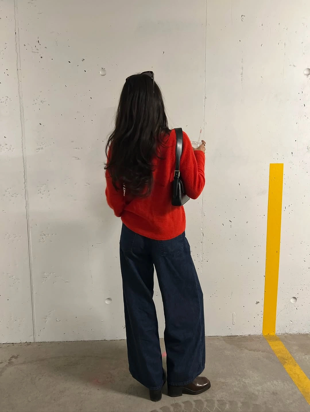 Red long-sleeve top with dark wide-leg jeans and black bag
