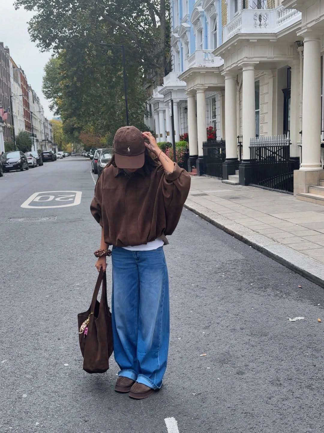 Woman in brown top and cap with wide blue jeans