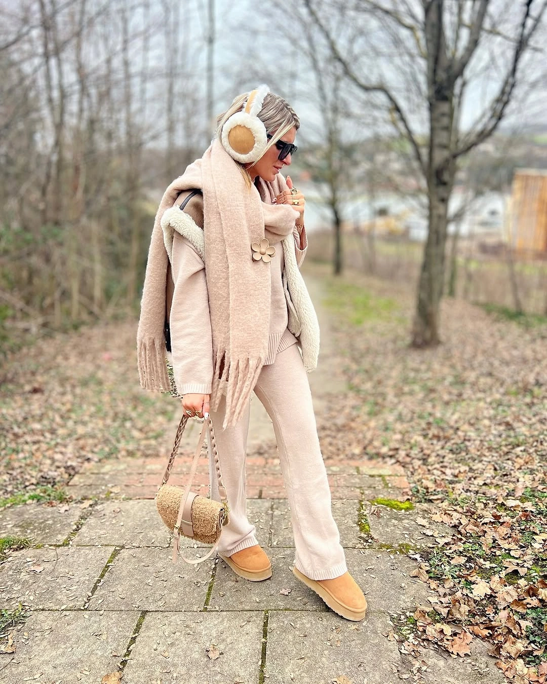 Woman in beige outfit with scarf, earmuffs, and small bag
