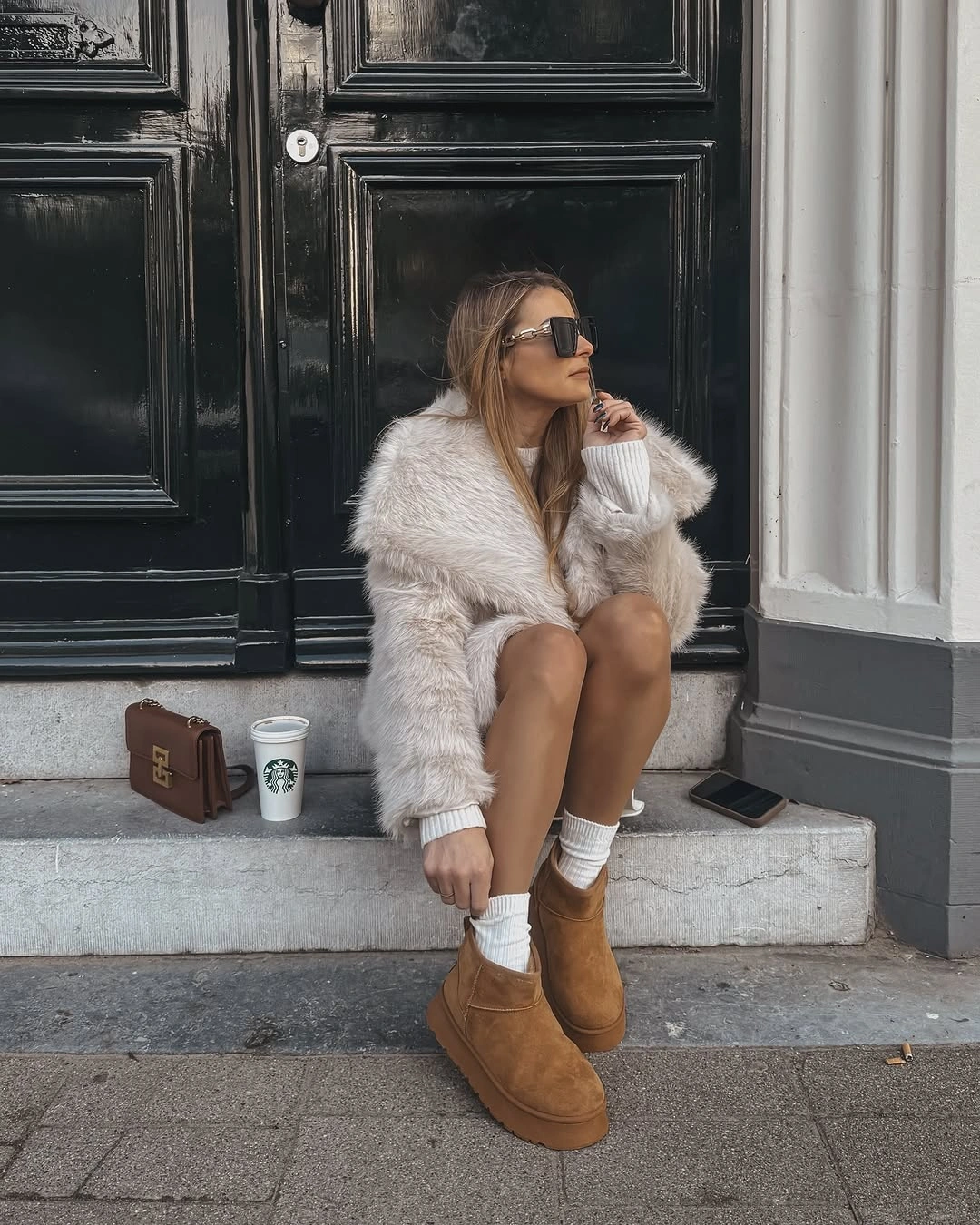 Seated woman in white fluffy coat, socks, and tan boots
