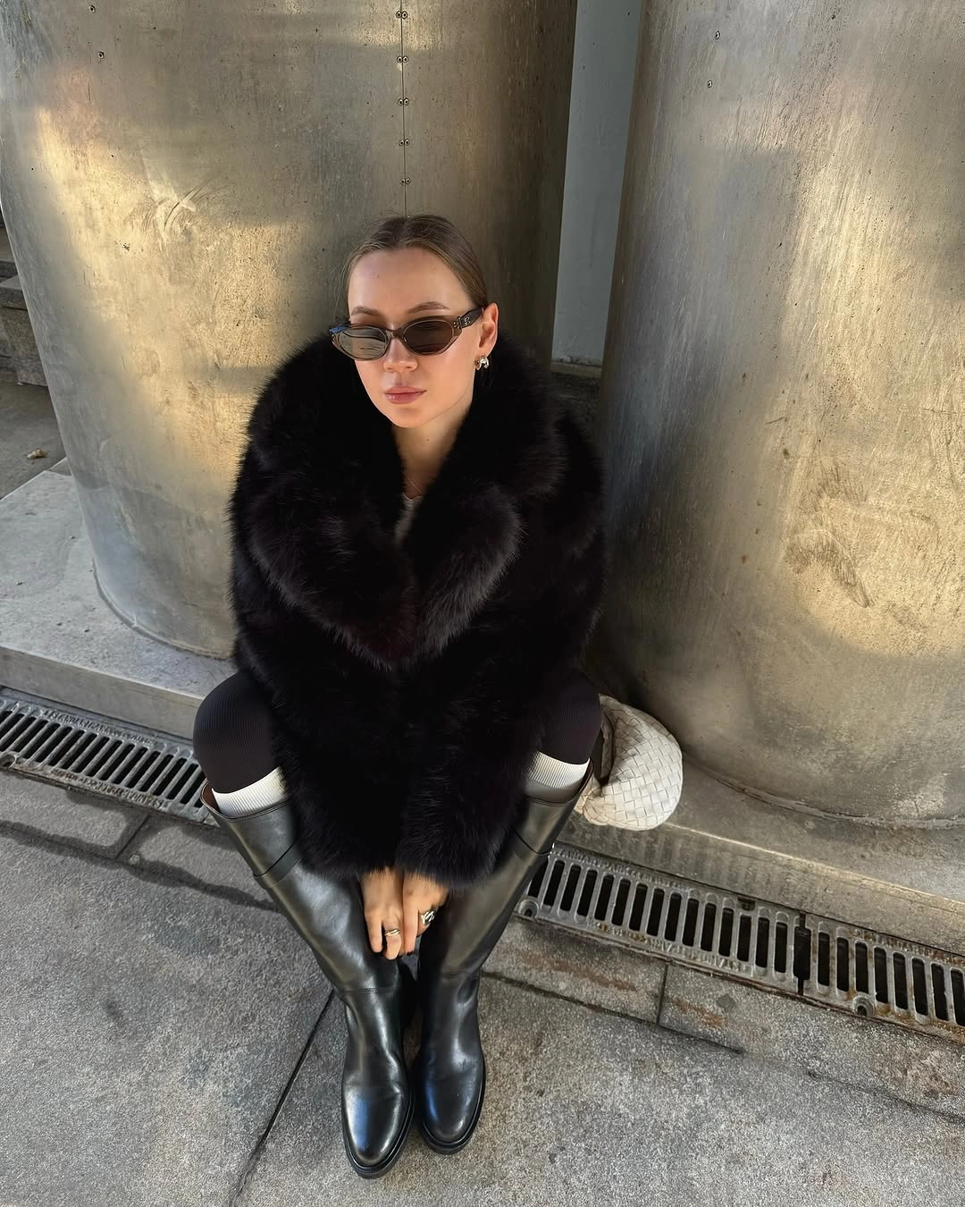 Seated woman in black plush-looking top and tall boots