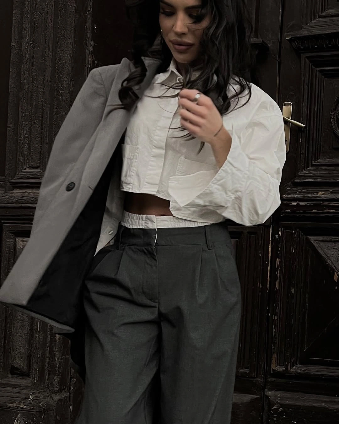 White cropped blouse under grey blazer with dark trousers