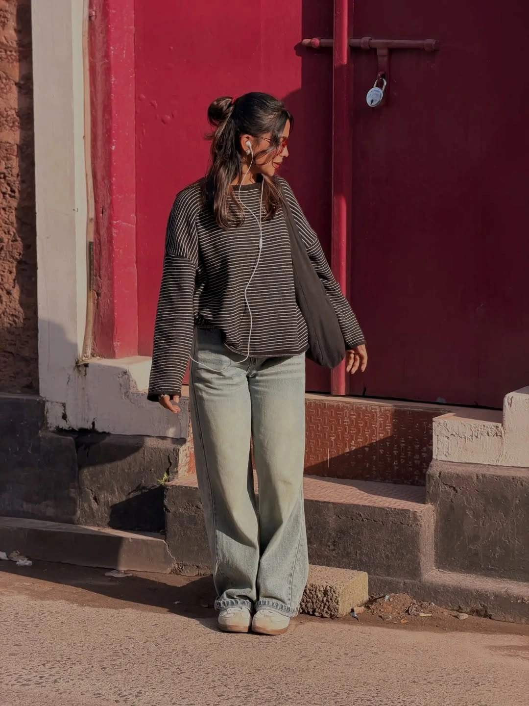 Woman in dark striped oversized top and pale wide-leg jeans
