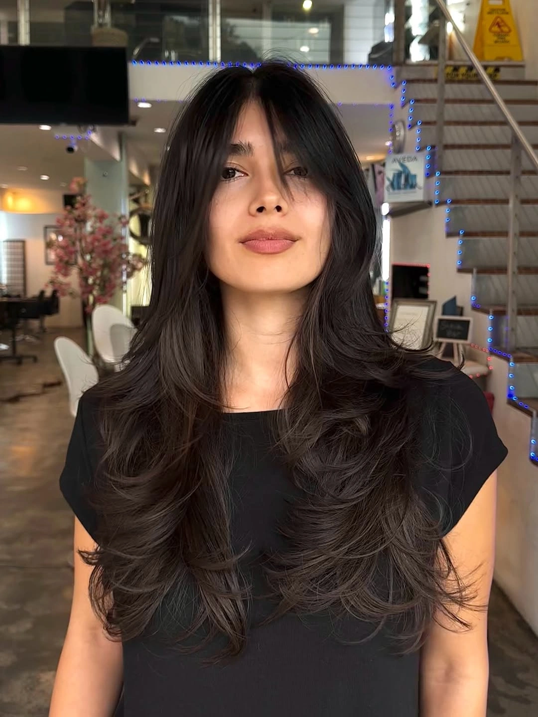 Long dark layered cut with curtain bangs and curved side pieces
