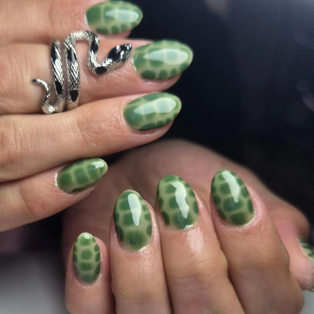 Rounded green nails with darker mottled spots and glossy finish