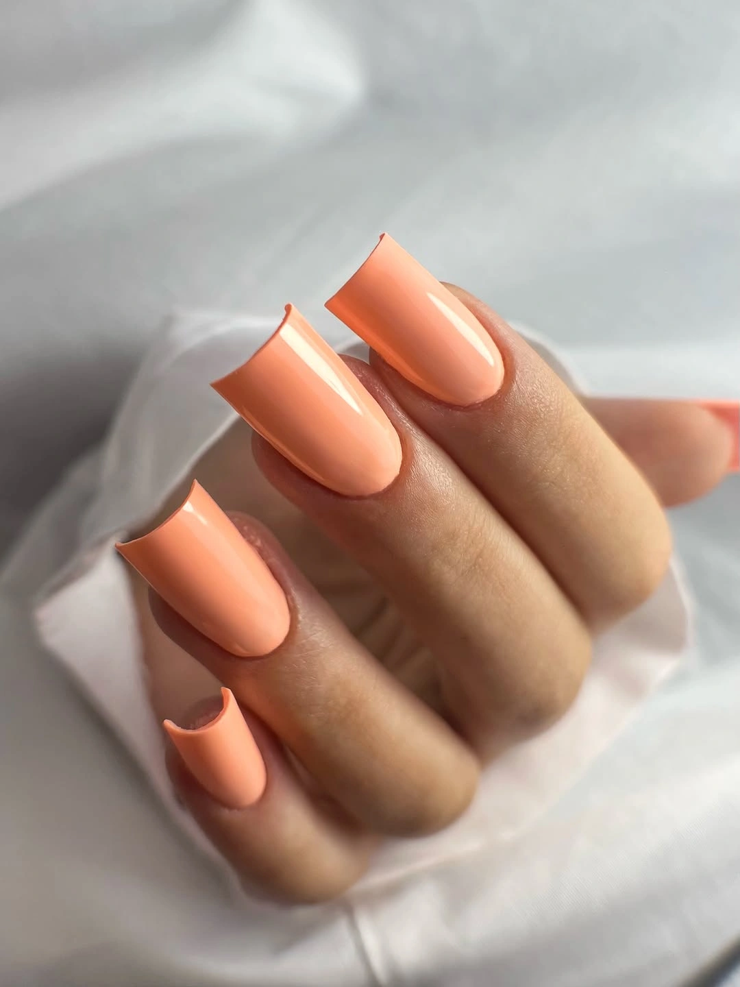 Long peach coffin nails with glossy squared tips and curved sides