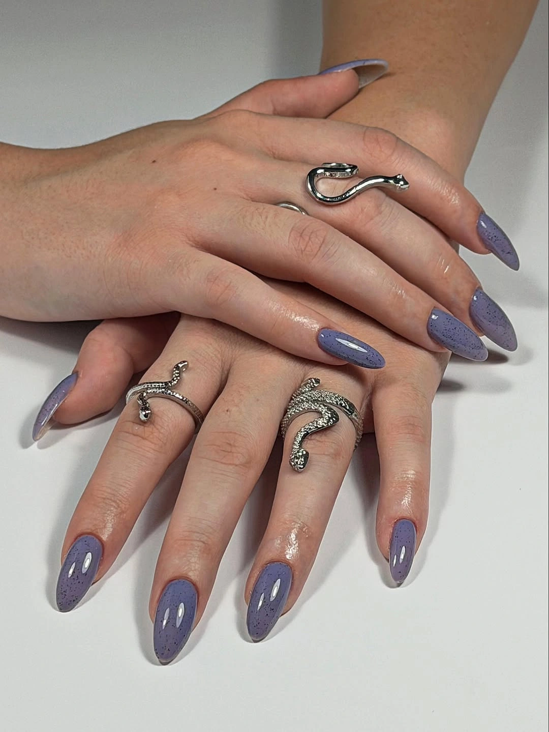 Lavender gray almond nails with scattered dark speckles and glossy shine