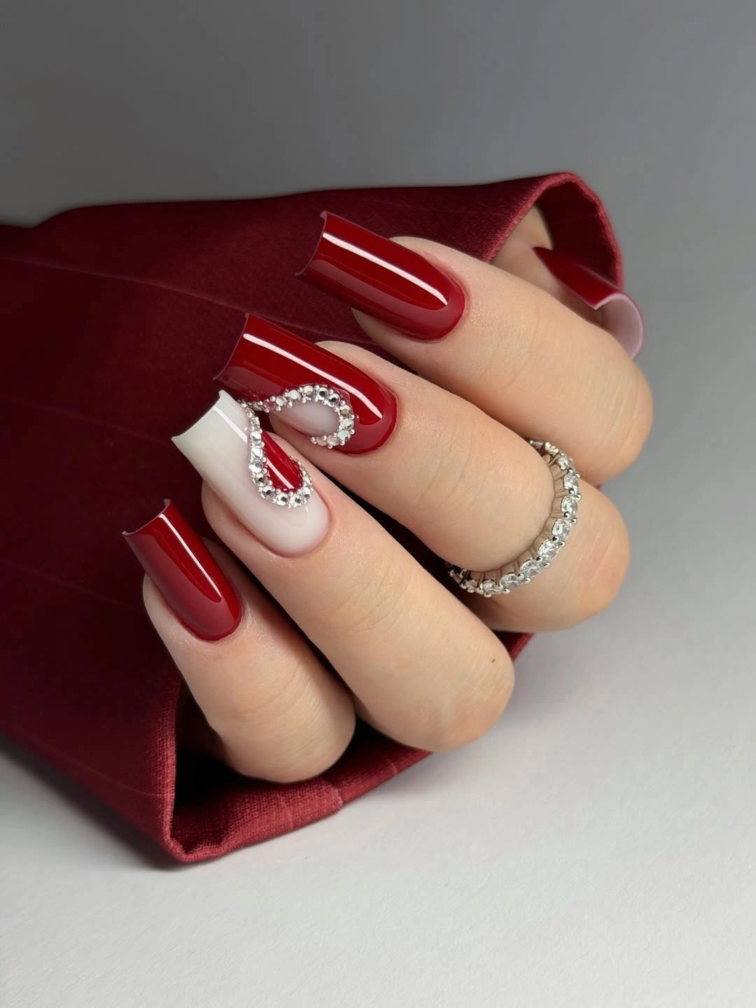 Long red square nails with white accents and clear-stone detail
