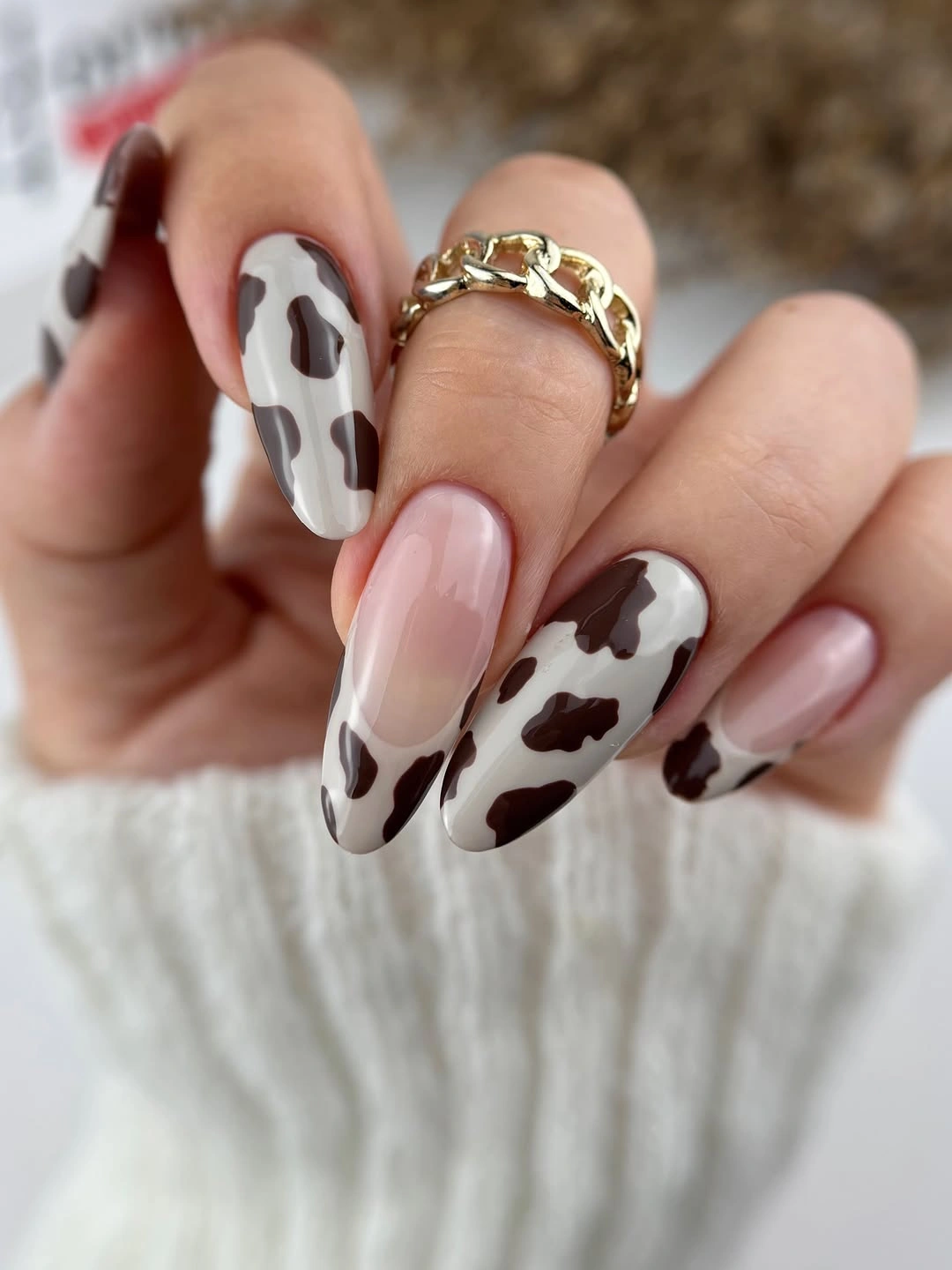 Long almond nails with brown cow print and glossy nude accents