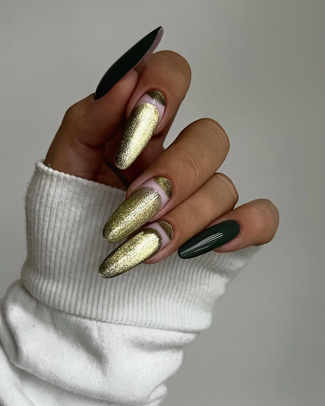 Pointed green nails with metallic-looking gold accents and glossy shine