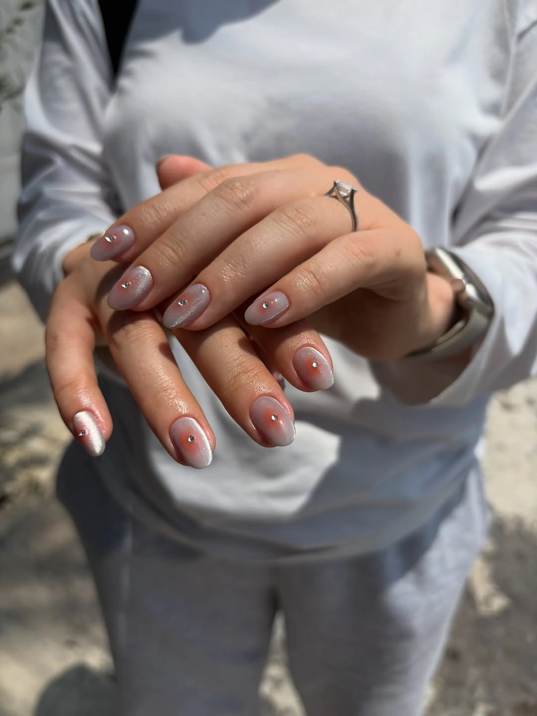 Short oval pale shimmer nails with small orange-centered dot accents