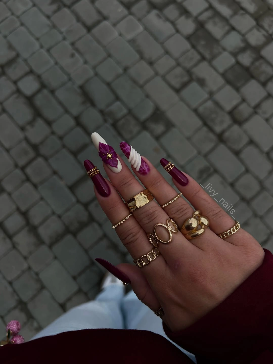 Long pointed plum nails with white accent and purple flower-like detail