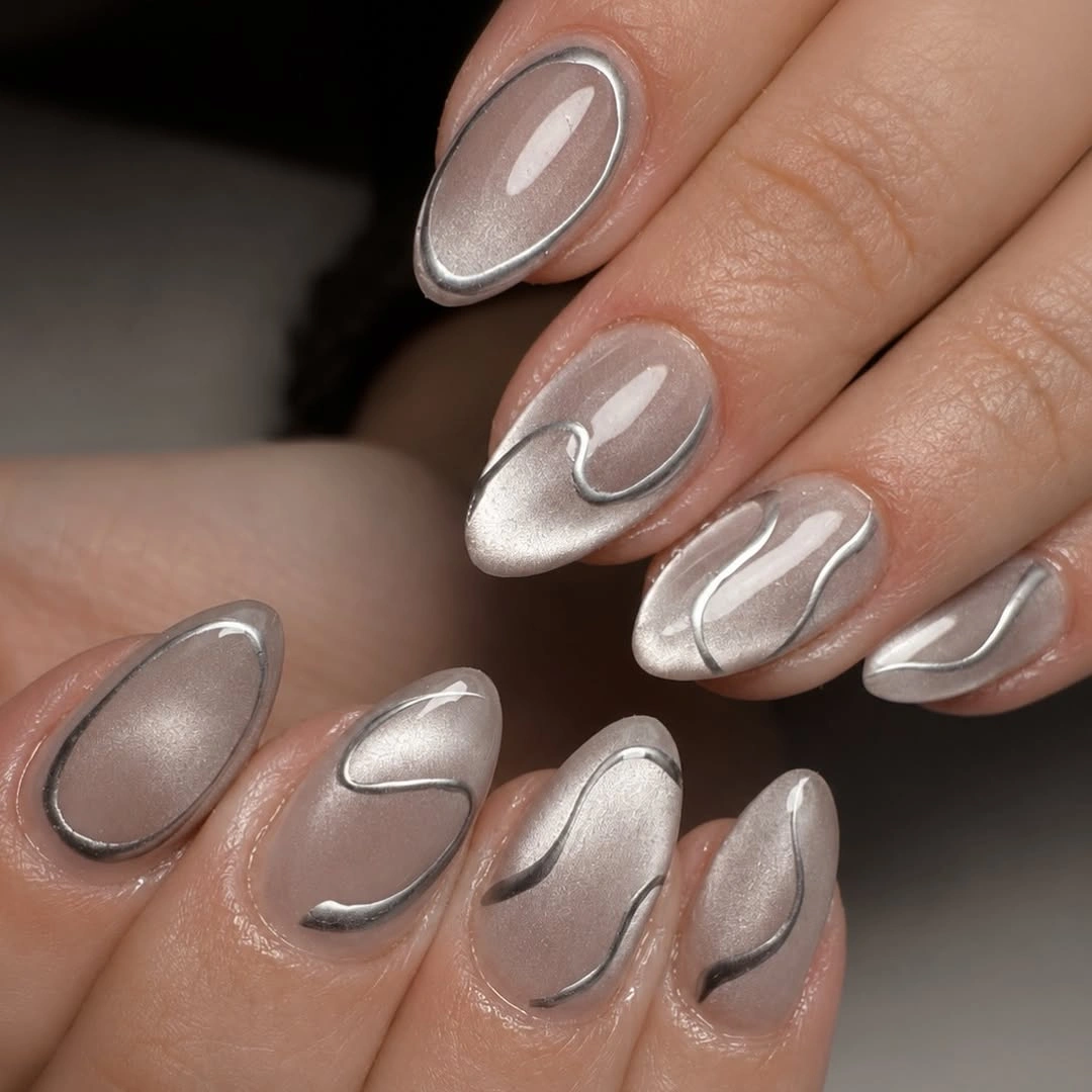 Medium almond nails with sheer gray bases and chrome-like curved lines