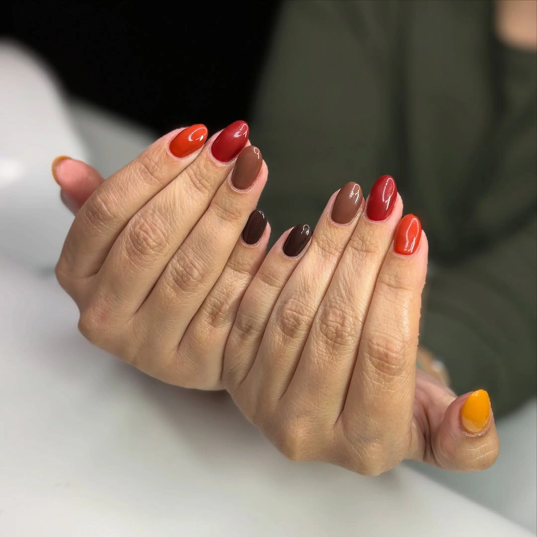 Short oval nails with glossy orange red brown and yellow tones
