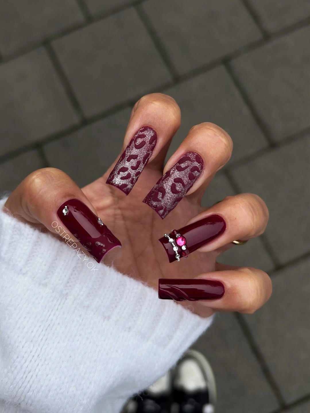 Long burgundy square nails with silver animal-like pattern and jewel-like tip accents
