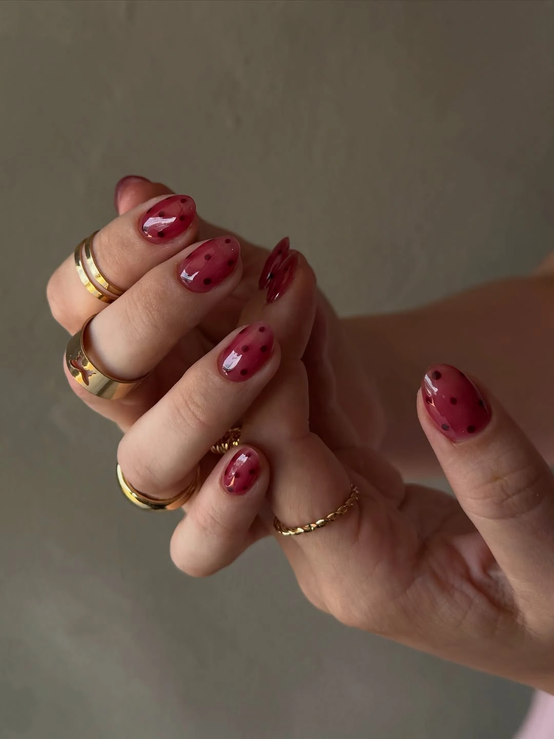 Short glossy berry nails with darker red areas and black dots
