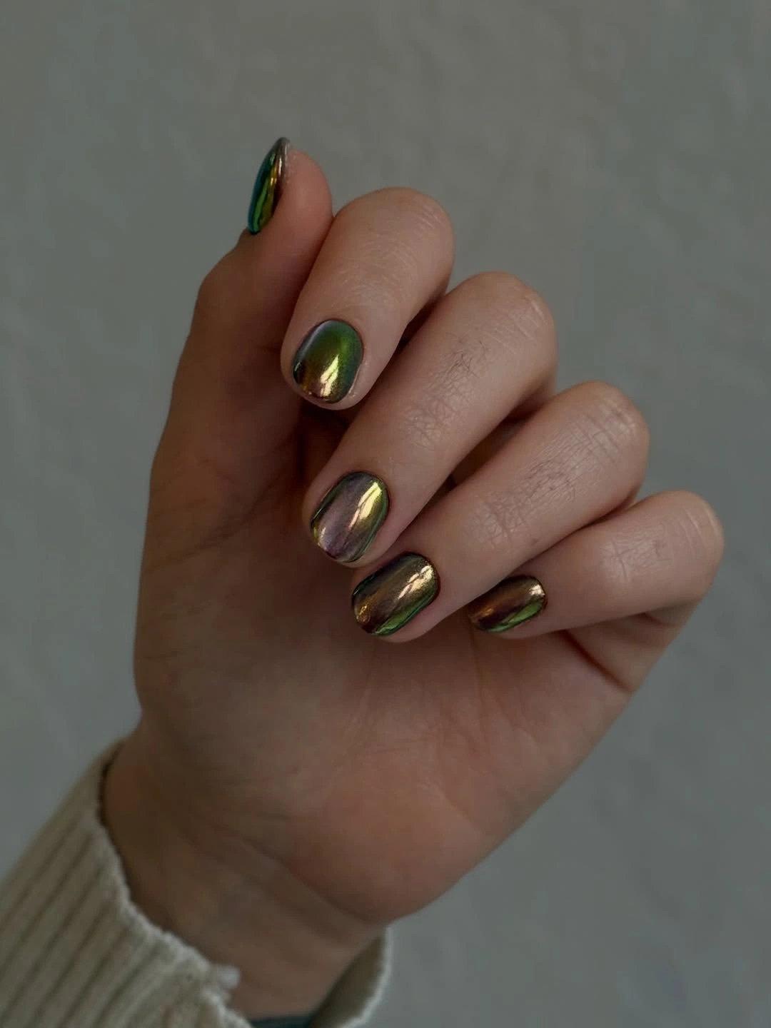 Short rounded nails with reflective olive, bronze, gold, and violet shifts