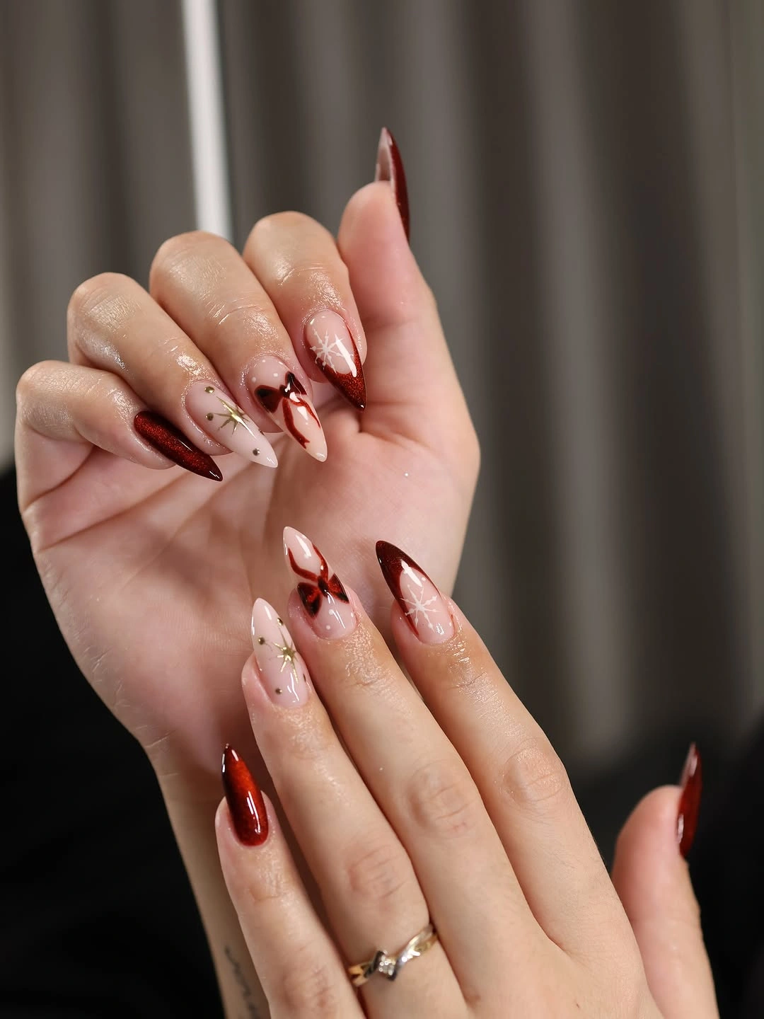 Long almond nails with red solids, blush space, curves, and gold accents