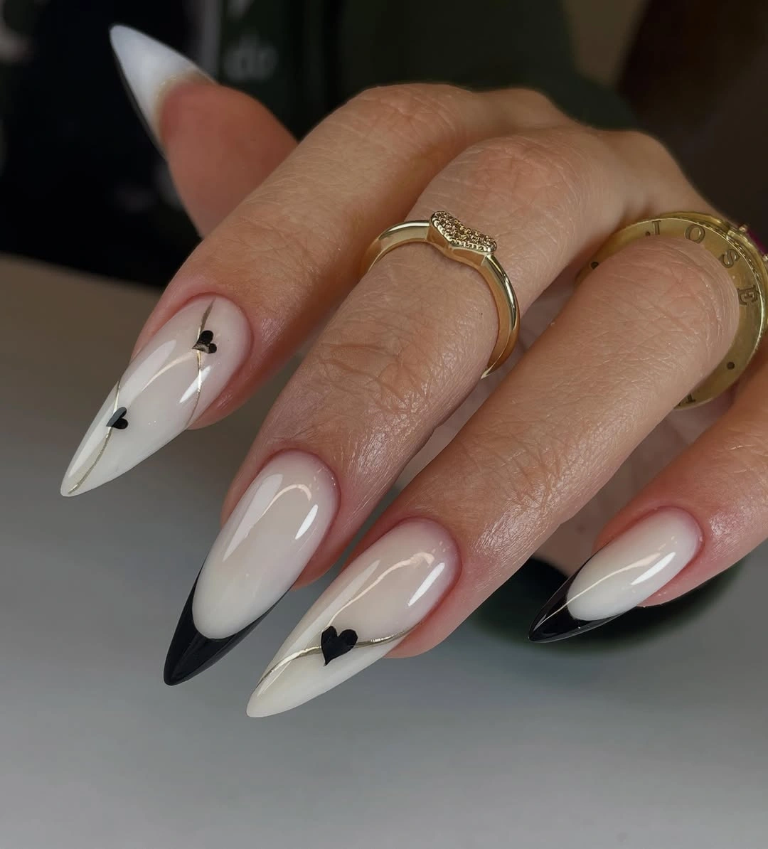 Long pointed almond nails with black tips, hearts, and fine lines
