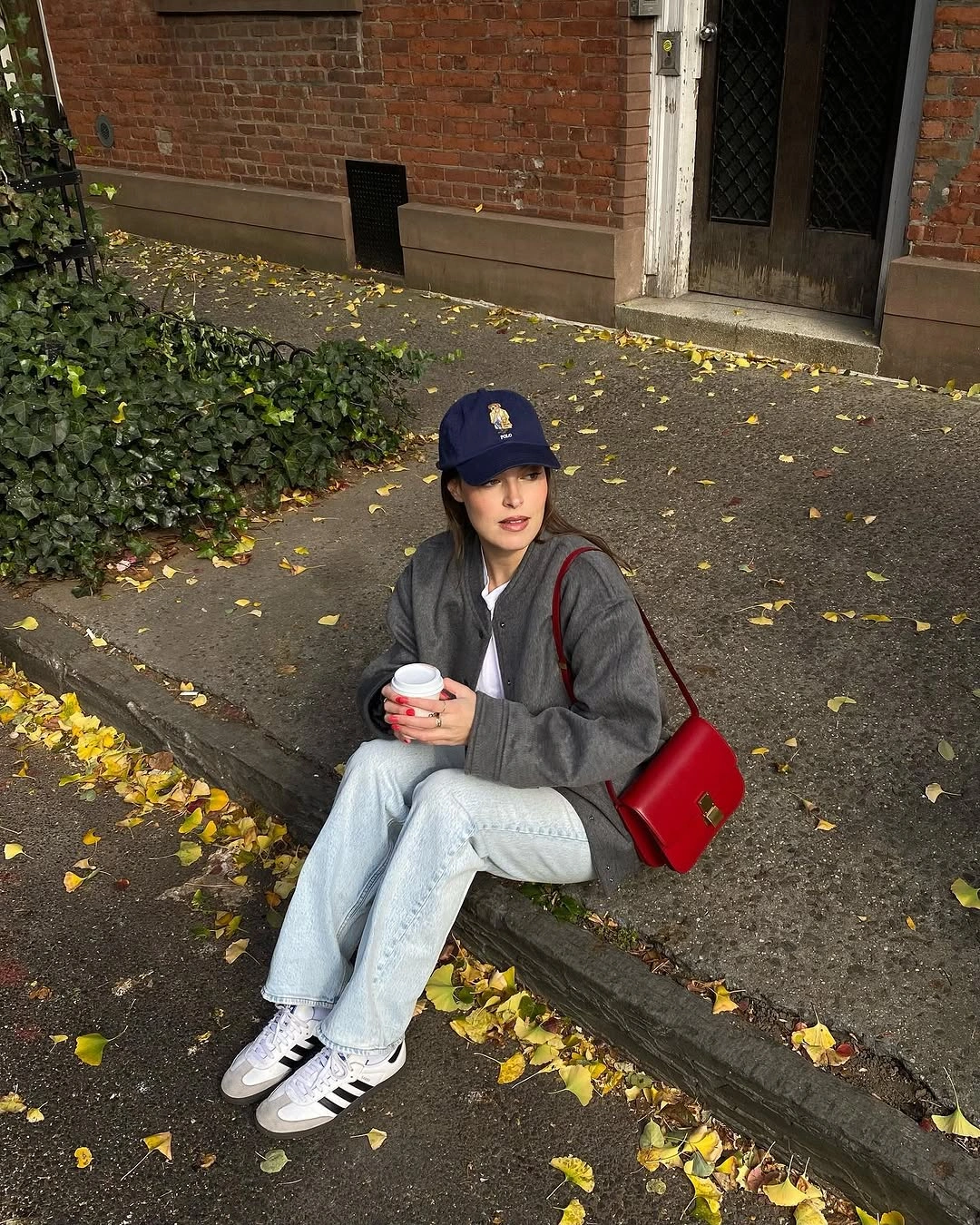 Gray oversized layer, navy cap, red crossbody bag, sneakers, light jeans