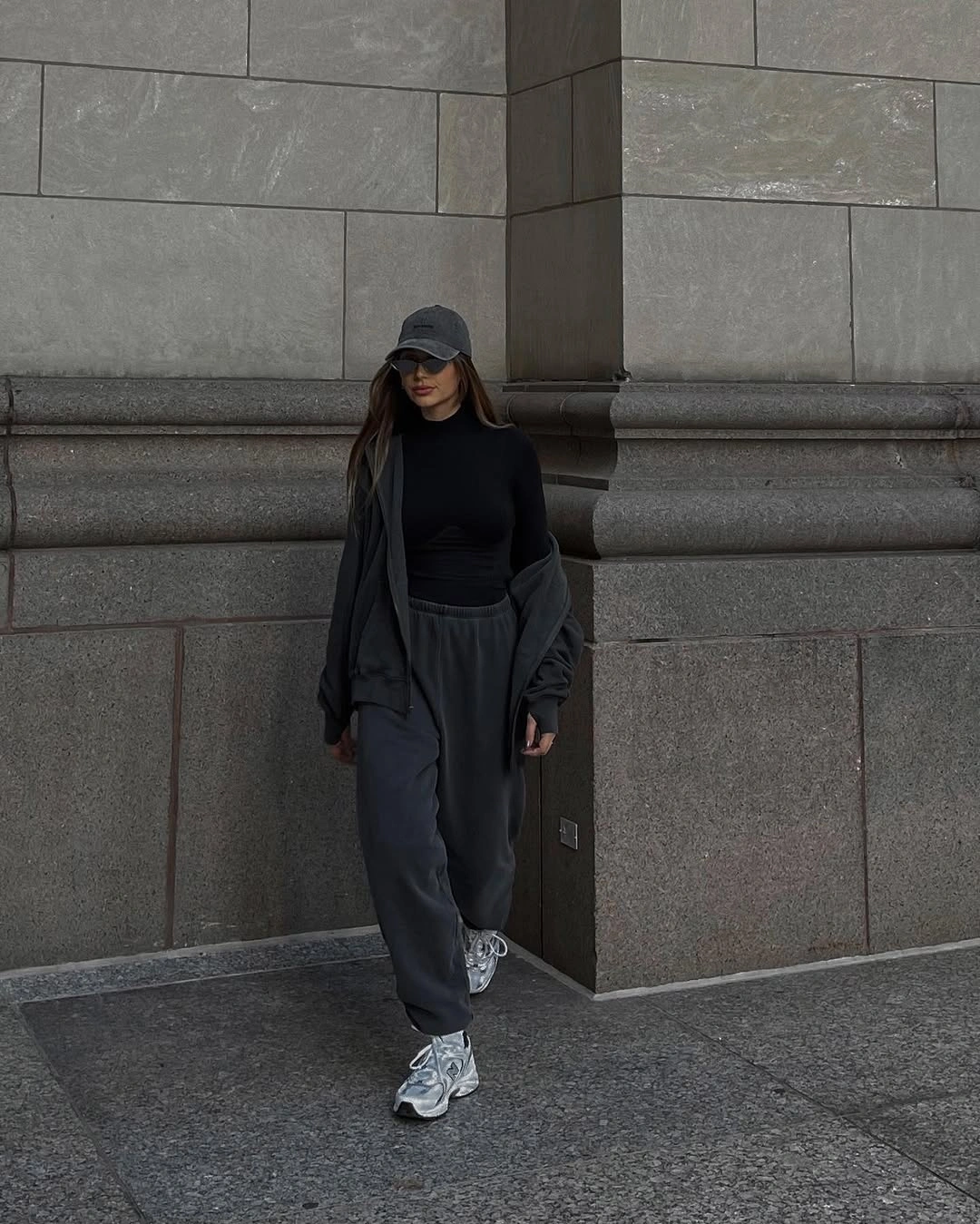 Black cap, fitted black top, wide gray pants, and silver sneakers