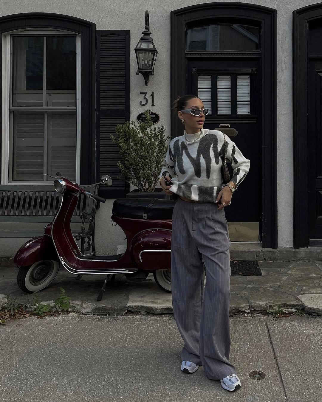 Cream sweater with black abstract pattern, gray pinstripe trousers, and sneakers