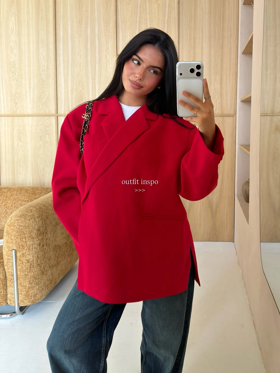 Bright red oversized coat, white neckline, dark jeans, and chain bag