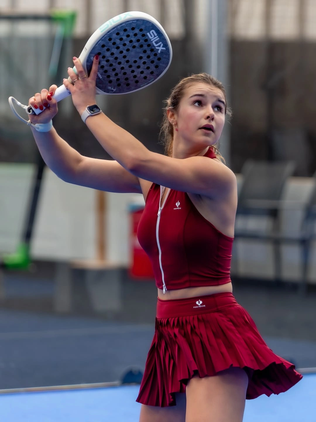 Deep red sleeveless padel set in raised racket position