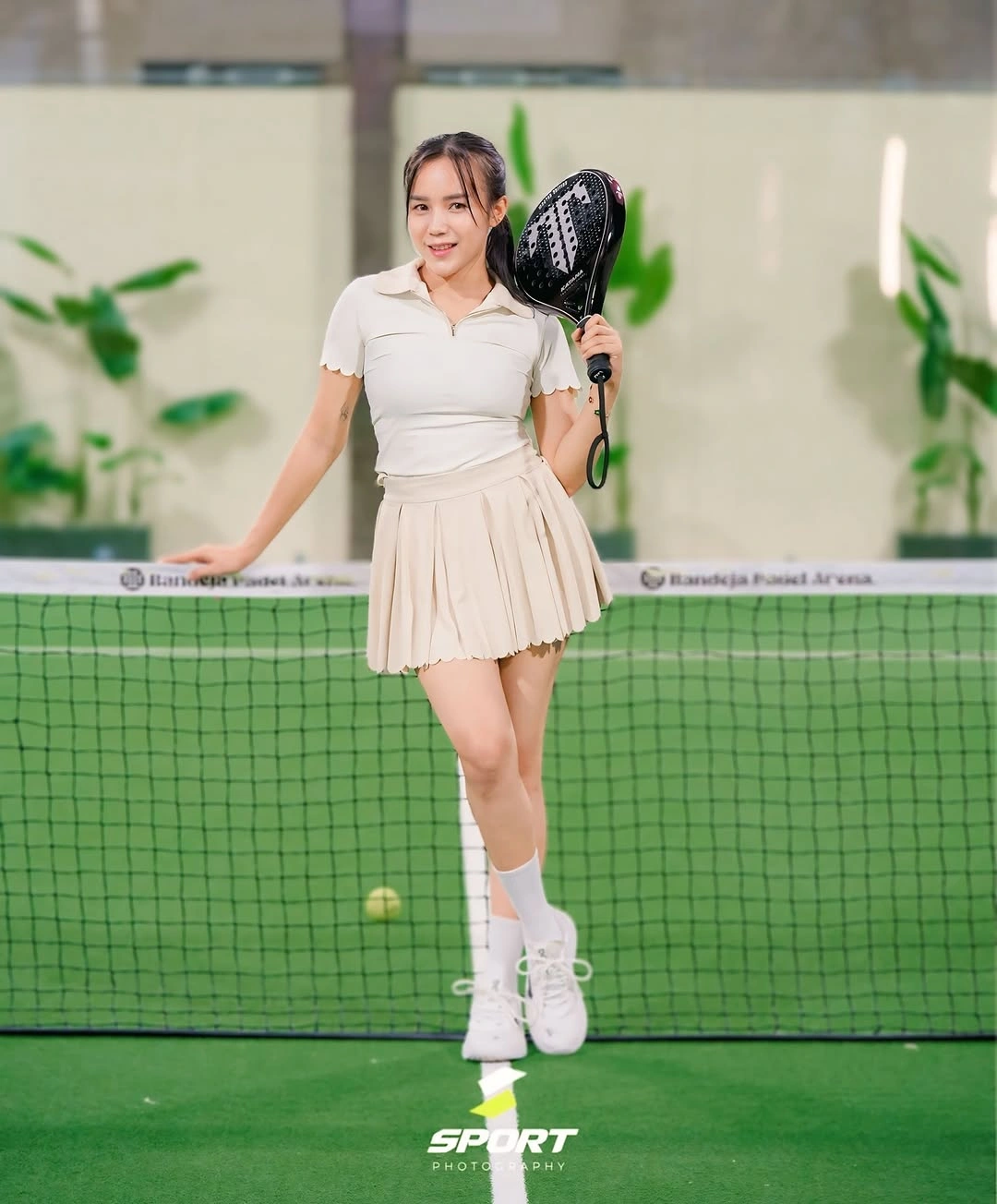 White collared top and beige pleated skirt with padel racket