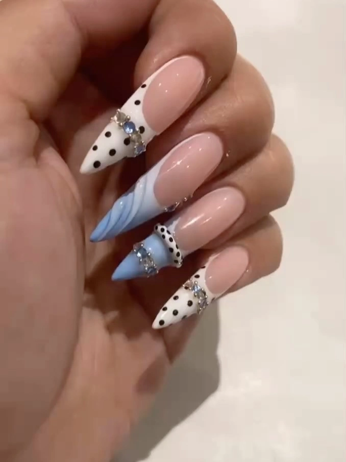 Blush almond nails with dotted white tips and pale blue accent
